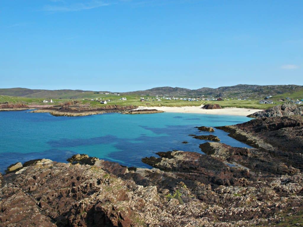 A stunning view of Clachtoll Beach in the Scottish Highlands, featuring golden sands, crystal-clear waters, and dramatic rock formations.